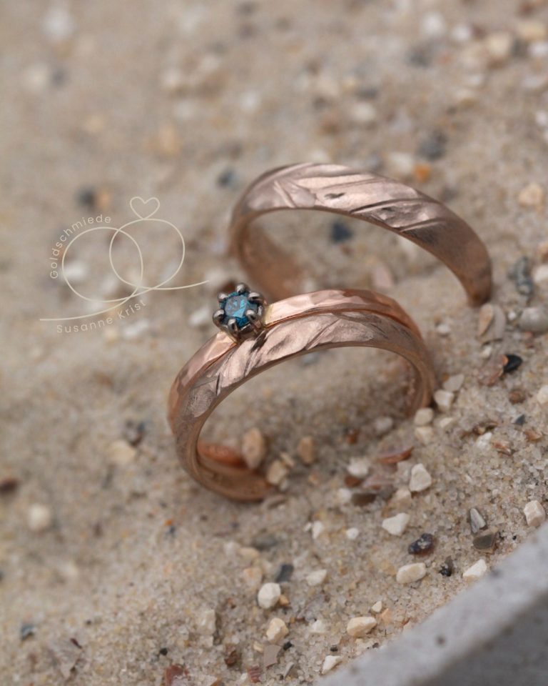Haselnussgold Ringe kaufen mit starker Struktur Geheime Bucht, dazu Rotgoldring mit blauem Stein